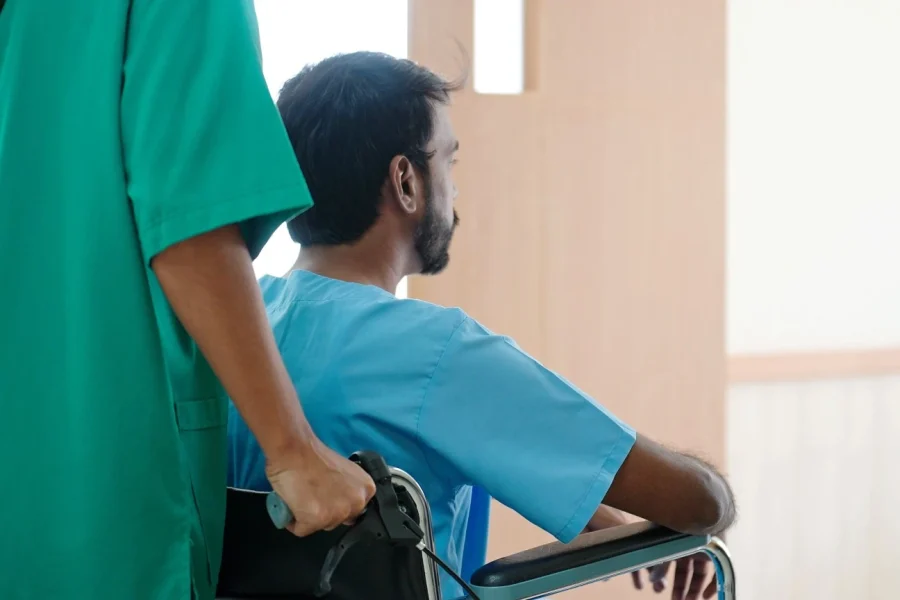 Man in wheelchair with nurse pushing him in home